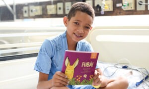 Criança do Hospita de Amor segurando livro Fubá