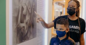 Educadora do ArtSampa dando aula para crianças na exposição no Plaza Sul
