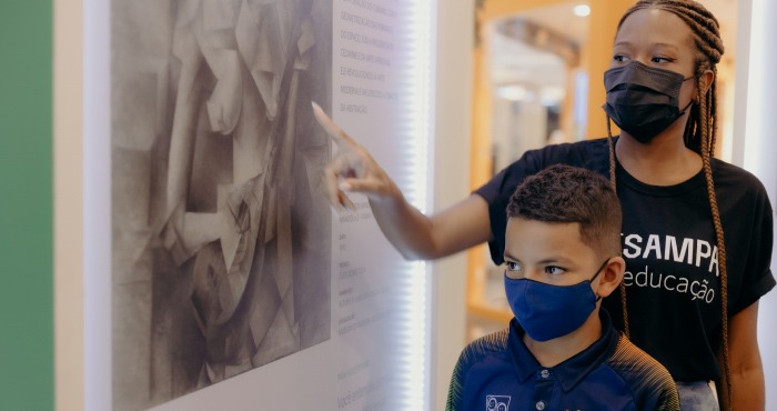 Educadora do ArtSampa dando aula para crianças na exposição no Plaza Sul